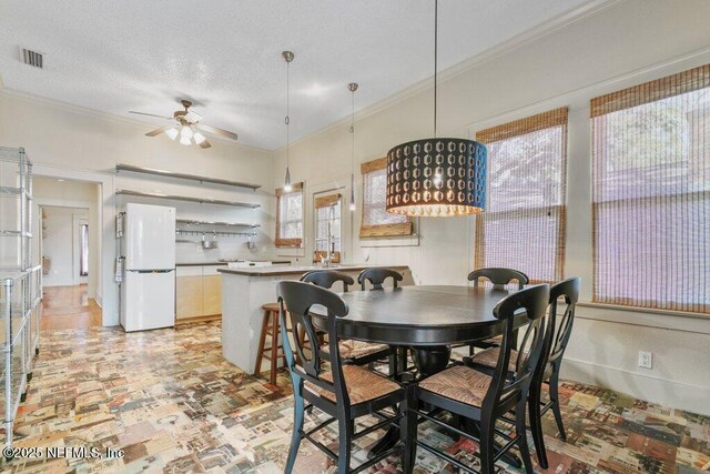 dining room featuring a textured ceiling, a ceiling fan, visible vents, and crown molding