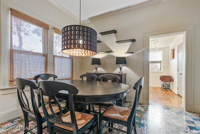 dining space featuring a textured ceiling, ornamental molding, attic access, and baseboards