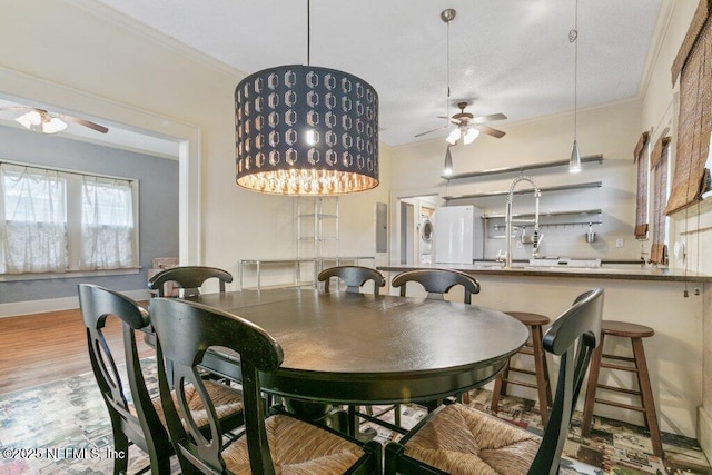 dining area with ornamental molding, ceiling fan, baseboards, and wood finished floors