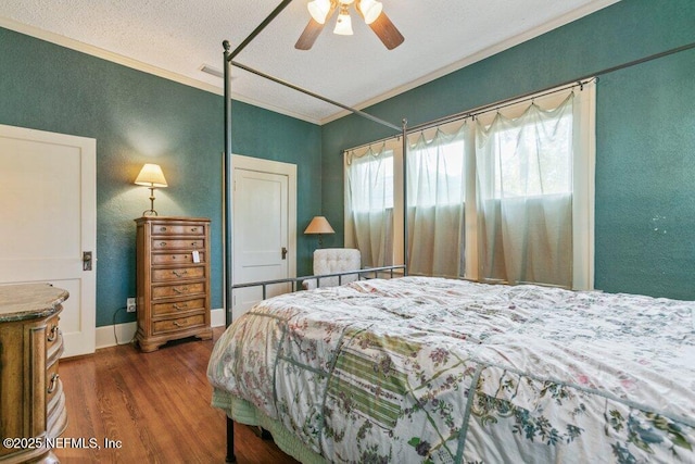 bedroom featuring dark wood finished floors, crown molding, baseboards, and ceiling fan