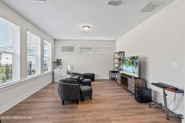 sitting room with light wood finished floors, visible vents, and a textured ceiling