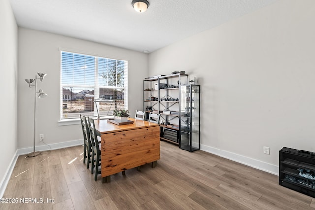 dining space with a textured ceiling, wood finished floors, and baseboards