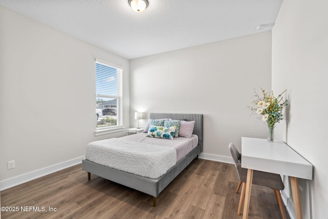 bedroom featuring a textured ceiling, wood finished floors, and baseboards