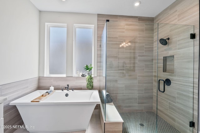 bathroom with a stall shower, a freestanding tub, and tile walls