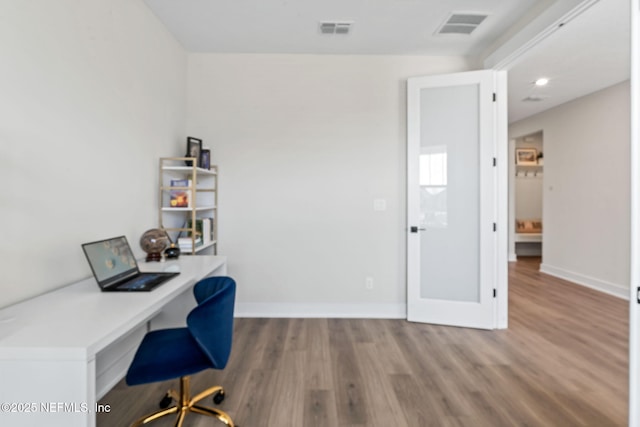 office with built in desk, wood finished floors, visible vents, and baseboards