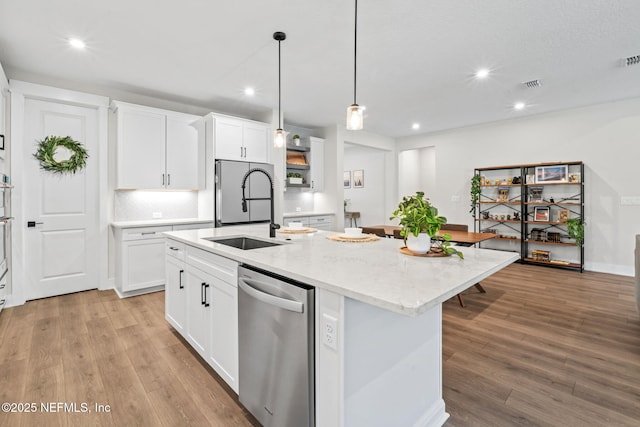 kitchen with a sink, light wood-style floors, dishwasher, and refrigerator