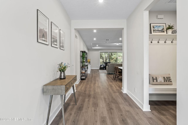 corridor with baseboards, wood finished floors, and recessed lighting