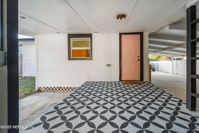 view of exterior entry with a patio and fence