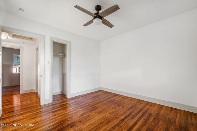 unfurnished bedroom with a ceiling fan, baseboards, dark wood finished floors, and a closet