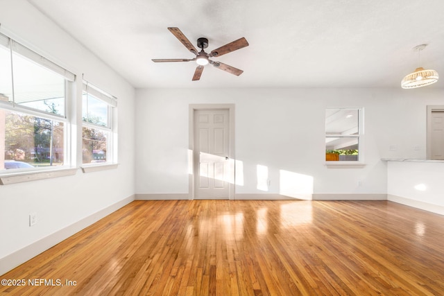 unfurnished living room featuring light wood-style floors, baseboards, and a ceiling fan