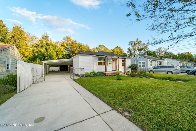 view of front facade with a carport, a front yard, concrete driveway, and fence