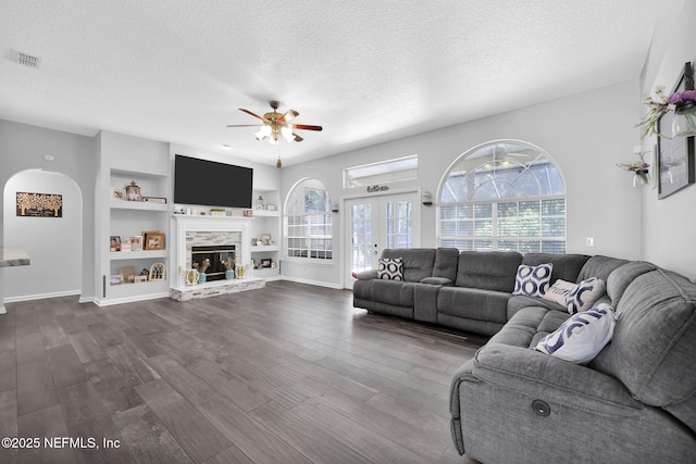 living area with visible vents, a textured ceiling, and wood finished floors