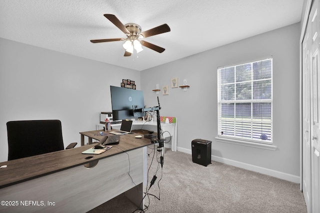 carpeted office space with a textured ceiling, plenty of natural light, a ceiling fan, and baseboards