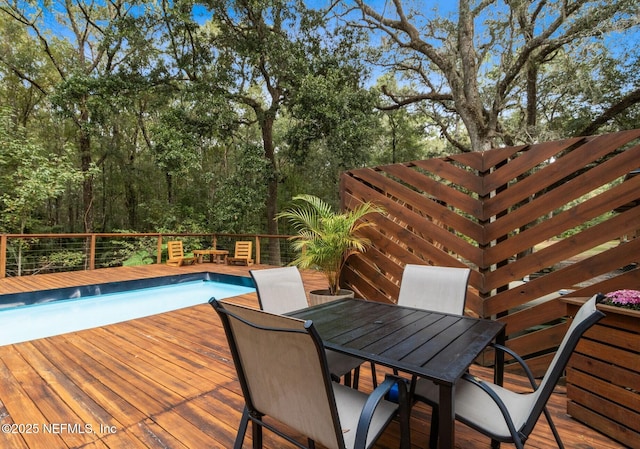 wooden terrace featuring outdoor dining area and a fenced in pool