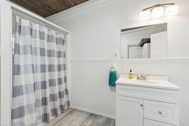 full bathroom featuring a shower with shower curtain, wooden ceiling, a wainscoted wall, wood finished floors, and vanity