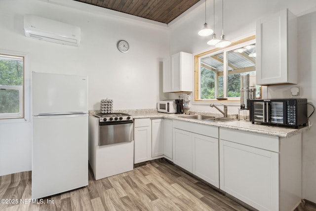 kitchen with a wall mounted AC, white cabinetry, a sink, light wood-type flooring, and white appliances