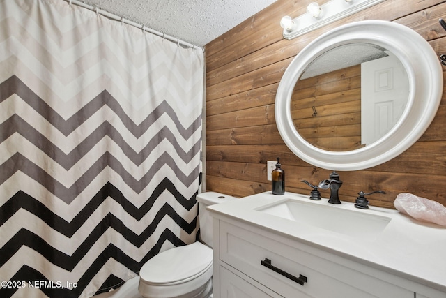 full bath with a textured ceiling, vanity, toilet, and wooden walls