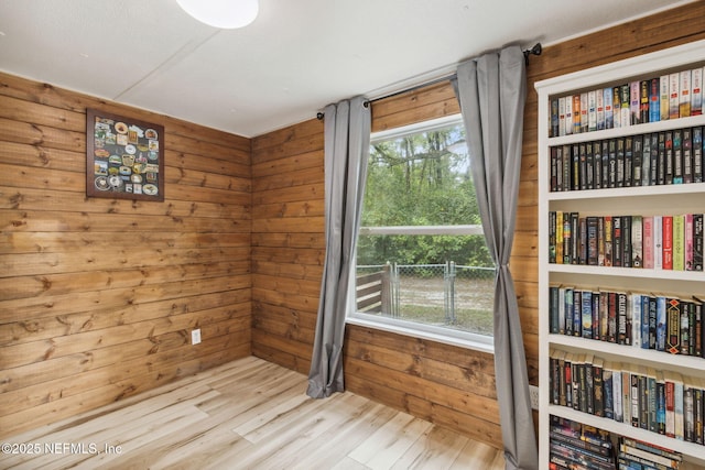 spare room featuring light wood-style floors and wooden walls