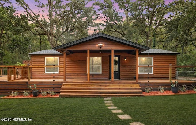 back of property at dusk featuring a lawn and a wooden deck