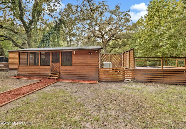 rear view of house featuring entry steps and fence