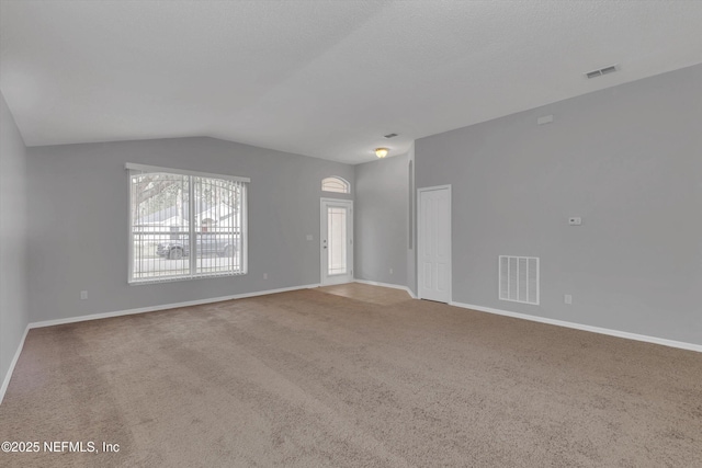 unfurnished living room with baseboards, visible vents, vaulted ceiling, and carpet flooring