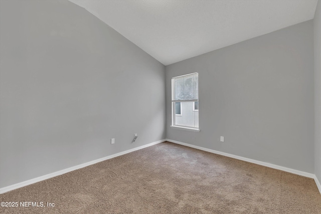 carpeted empty room featuring lofted ceiling and baseboards