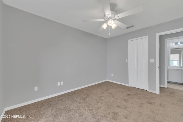 unfurnished bedroom featuring a closet, visible vents, light carpet, ceiling fan, and baseboards