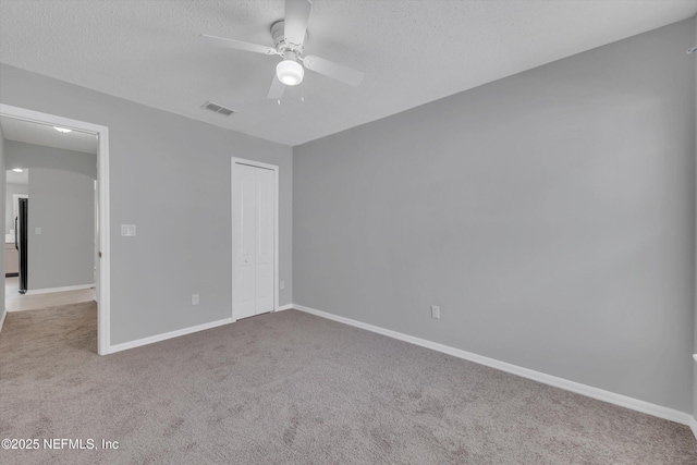 unfurnished bedroom featuring light carpet, baseboards, visible vents, a textured ceiling, and a closet