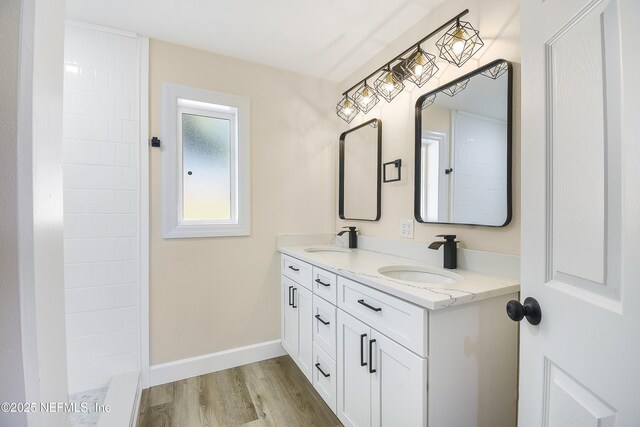 bathroom featuring double vanity, baseboards, a sink, and wood finished floors