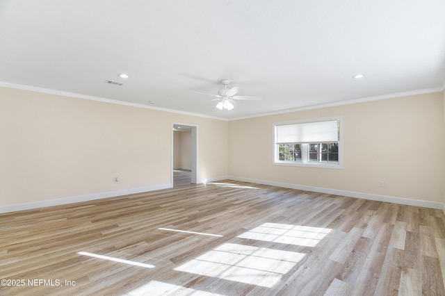 empty room with ornamental molding, light wood-style floors, visible vents, and baseboards