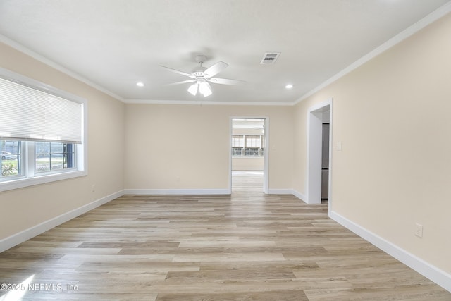 empty room with a wealth of natural light, visible vents, and crown molding