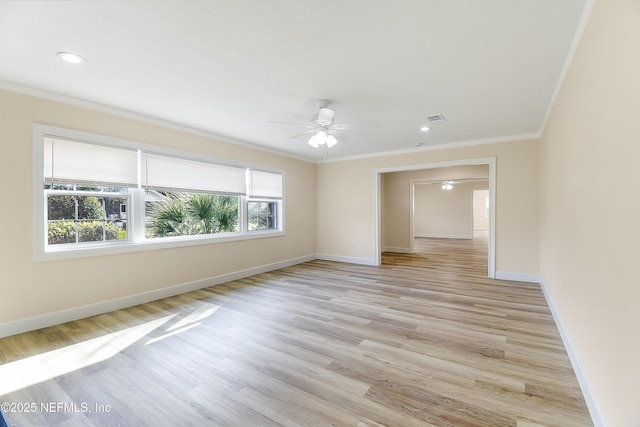 spare room with light wood-style flooring, visible vents, a ceiling fan, baseboards, and ornamental molding