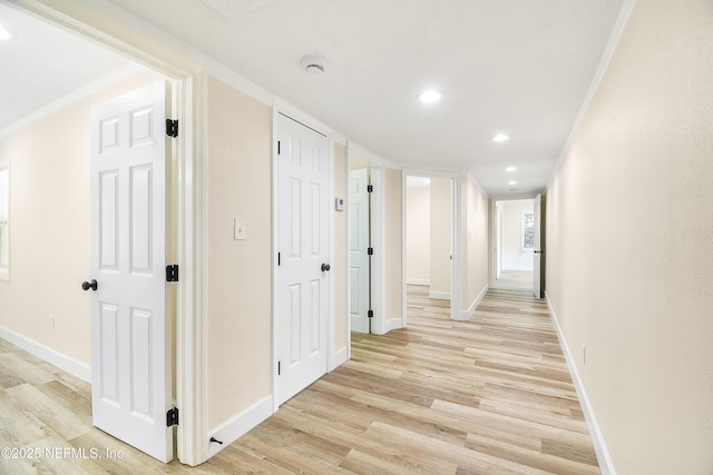 hall featuring ornamental molding, light wood-style flooring, and baseboards