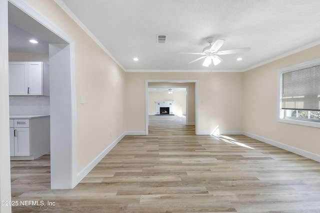 empty room with ornamental molding, light wood-style flooring, and baseboards