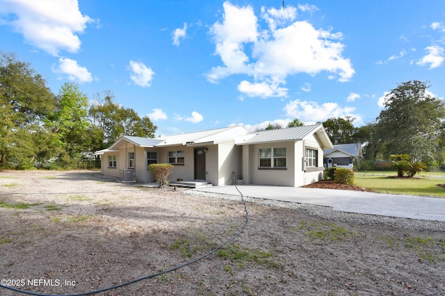 single story home featuring metal roof and central AC