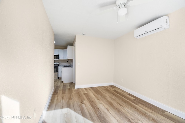 interior space featuring light wood-style flooring, baseboards, a sink, and a wall mounted AC