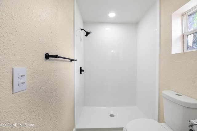 full bath featuring toilet, a stall shower, and a textured wall