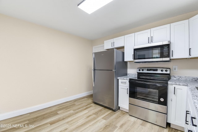 kitchen with light wood-style flooring, white cabinetry, stainless steel appliances, and baseboards