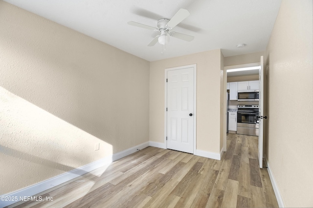 unfurnished bedroom featuring light wood-style flooring, baseboards, and ceiling fan