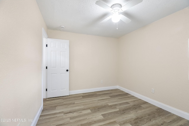 empty room featuring a textured ceiling, ceiling fan, baseboards, and light wood-style floors