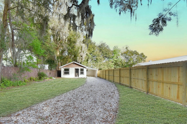 yard at dusk featuring fence and an outdoor structure