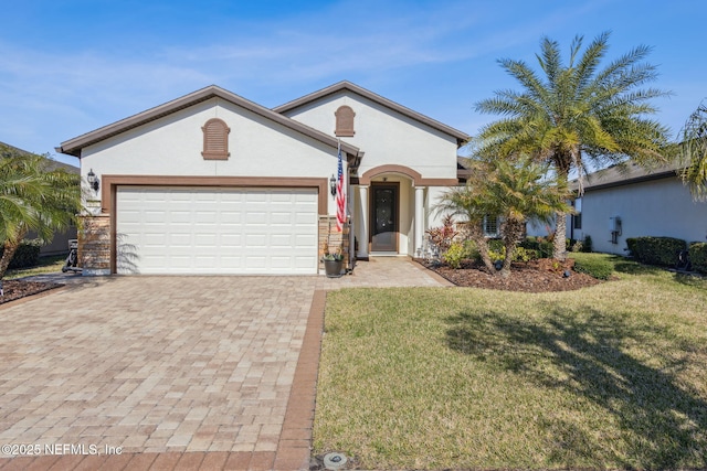 view of front facade featuring an attached garage, stucco siding, decorative driveway, and a front yard