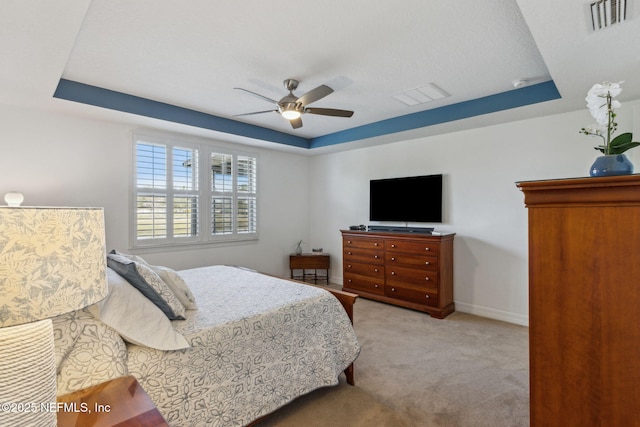 bedroom featuring a raised ceiling, visible vents, light carpet, and baseboards