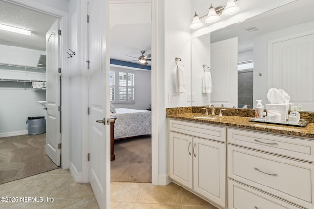 ensuite bathroom with ceiling fan, tile patterned flooring, visible vents, vanity, and ensuite bath