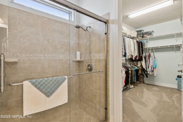 bathroom with a shower stall, a textured ceiling, and a spacious closet