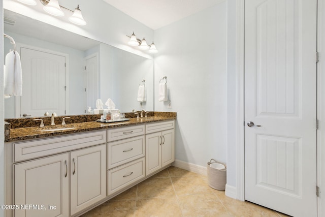 bathroom with double vanity, baseboards, a sink, and tile patterned floors