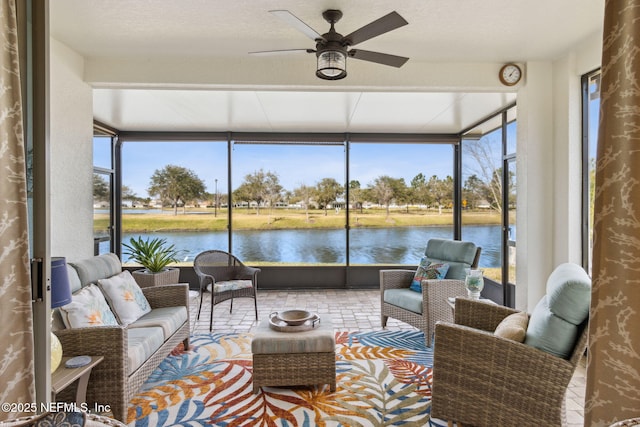 sunroom / solarium featuring a water view, plenty of natural light, and ceiling fan