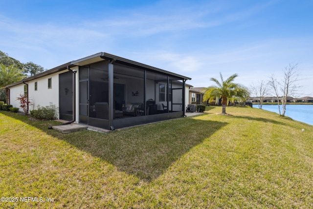 rear view of house with a yard, a water view, and a sunroom