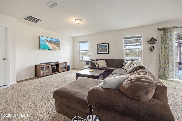 carpeted living area featuring a textured ceiling, visible vents, and baseboards