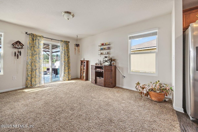 interior space with dark colored carpet, a textured ceiling, and baseboards